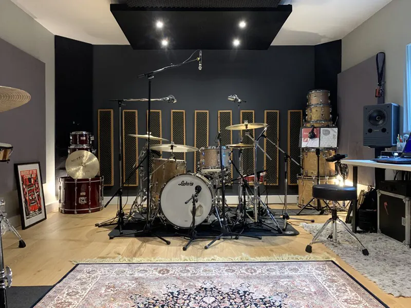music practice room for drumming. Full drum set on a soundproof mat. Acoustic wall panel about drum kit, down lights, acoustic panels on walls. 