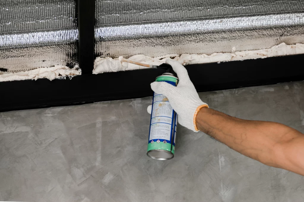 human hand white glove are caulking roof leaks with canned caulk foam
