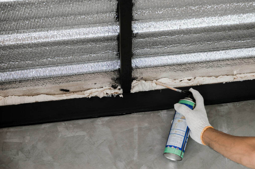 person spraying expanding foam into a crack on wall