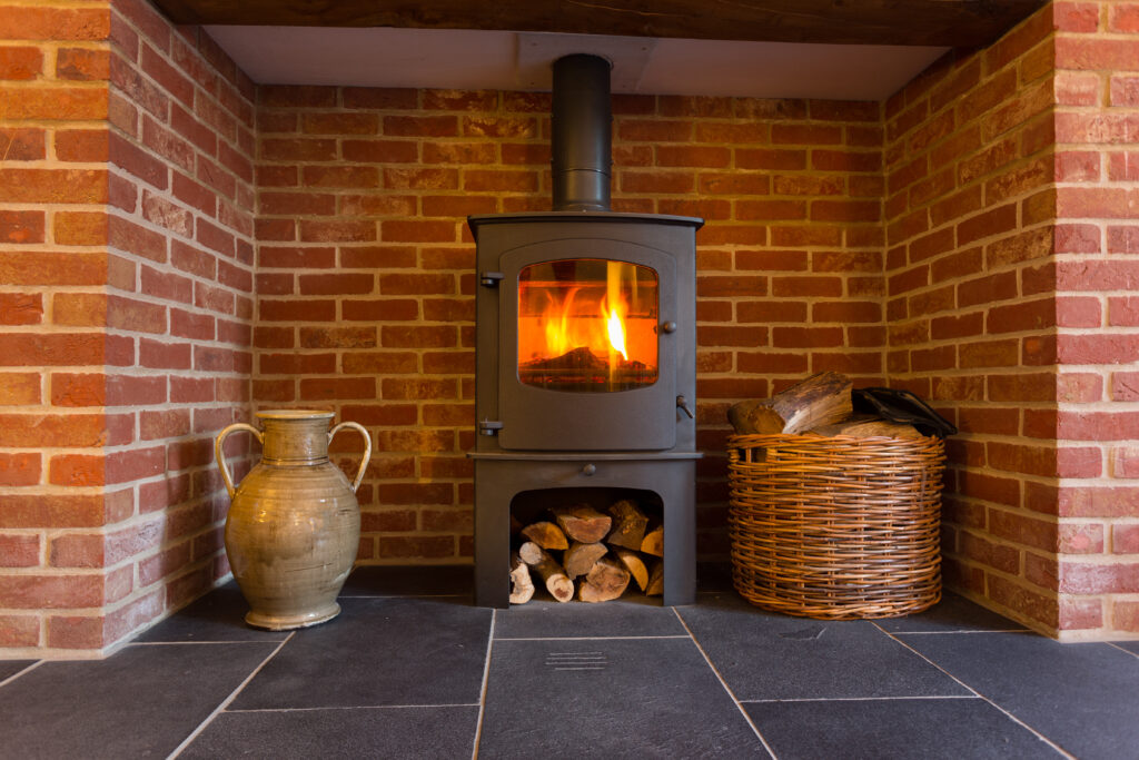 roaring fire inside wood burning stove brick fireplace with basket cut wood ready burning